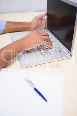 Mid section of businessman using laptop at desk