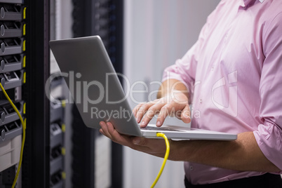 Mid section of a technician typing on his notebook