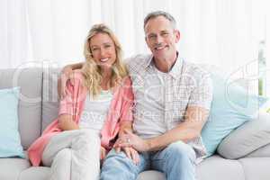 Happy couple relaxing on the couch smiling at camera