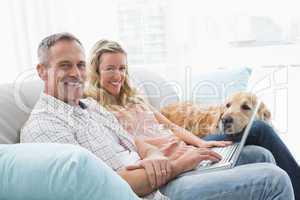 Couple using laptop and spending time with their dog