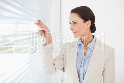 Businesswoman looking out the blinds