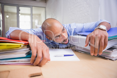 Tired businessman with stack of files on desk