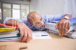 Tired businessman with stack of files on desk