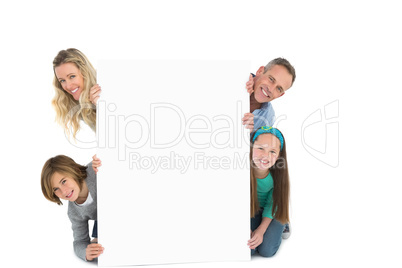 Cute family smiling at camera holding poster