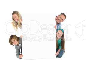 Cute family smiling at camera holding poster