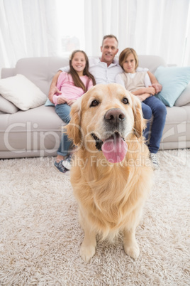 Family sitting on the couch with golden retriever in foreground