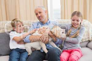 Father with his children on sofa playing with puppy
