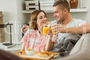Cute couple relaxing on couch with breakfast