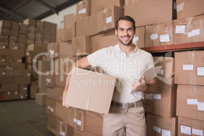 Delivery man with box and clipboard in warehouse