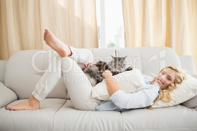 Happy blonde with pet cat on sofa