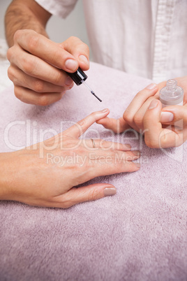 Manicurist painting a customers nails