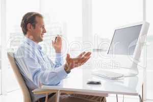 Smiling businessman sitting at his desk on video chat