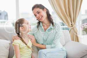 Cute mother and daughter smiling at each other