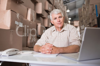 Warehouse manager with laptop at desk