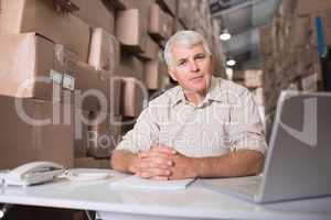 Warehouse manager with laptop at desk