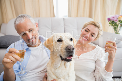 Happy couple with their pet dog drinking champagne