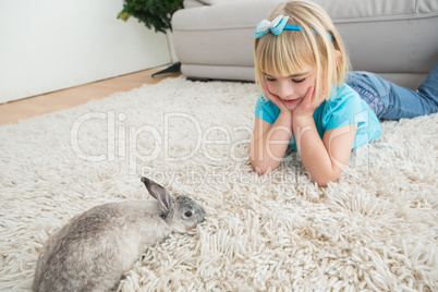 Little girl lying on rug with rabbit