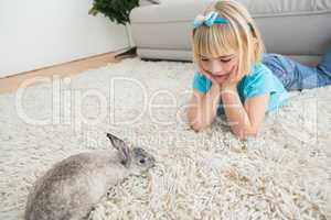 Little girl lying on rug with rabbit