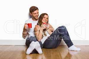 Couple with coffee cups sitting on floor