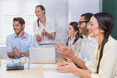Smiling business people clapping during a meeting