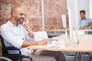 Businessman in wheelchair working at his desk on the phone