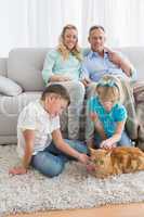 Smiling family with their ginger cat on the rug