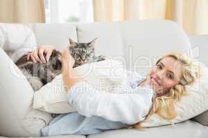 Happy blonde with pet cat on sofa