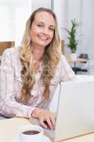 Businesswoman using laptop at her desk and having coffee
