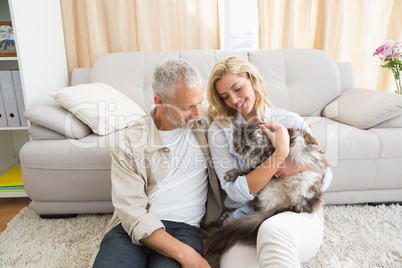 Happy couple with pet cat on floor