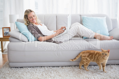 Pretty woman lying on sofa using her laptop