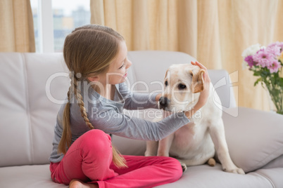 Cute little girl with her puppy on couch