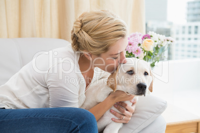 Happy blonde cuddling with puppy on sofa