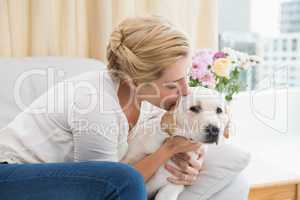 Happy blonde cuddling with puppy on sofa