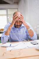 Tired businessman with paperwork at desk