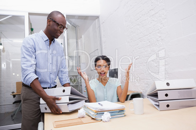 Businesswoman surprised with stack of folders at desk