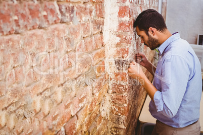 Thoughtful businessman standing against brick wall
