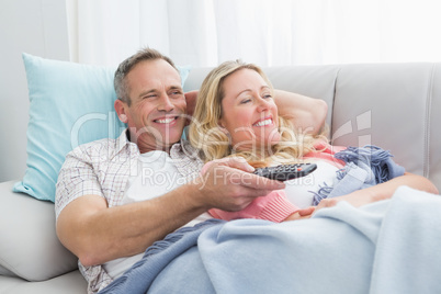 Happy couple cuddling on the couch watching television