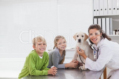 Smiling vet examining a dog with its owners