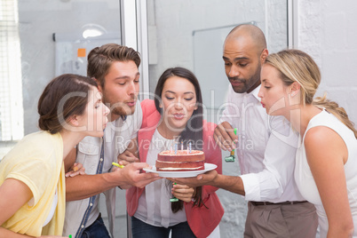 Businesswoman blowing the candles on her birthday cake