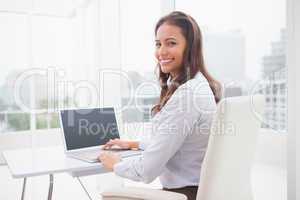 Smiling businesswoman using laptop at her desk