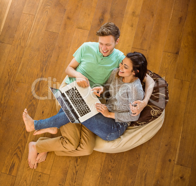 Cute couple using laptop on beanbag