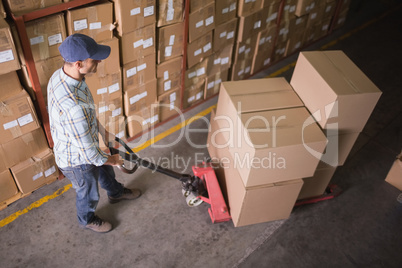 Worker pushing trolley with boxes in warehouse