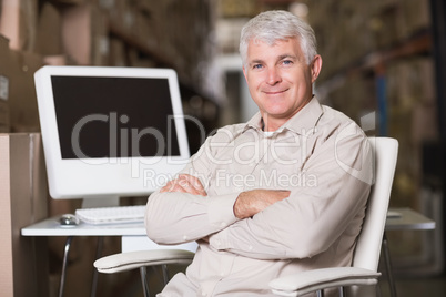 Smiling warehouse manager with computer