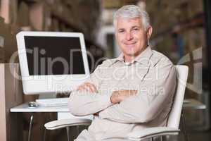 Smiling warehouse manager with computer