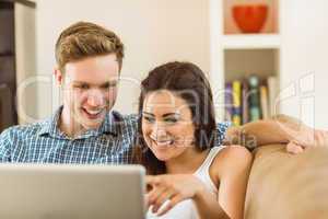 Happy young couple relaxing on the couch with laptop