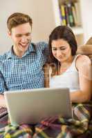 Happy young couple relaxing on the couch with laptop