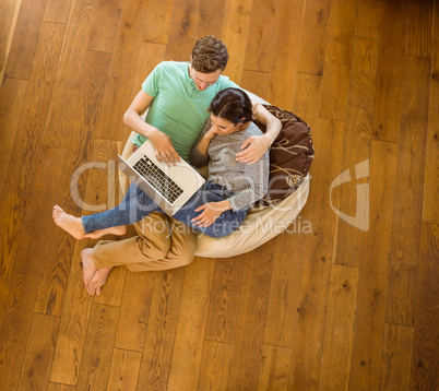 Cute couple using laptop on beanbag