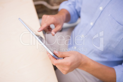 Mid section of businessman using digital tablet at desk