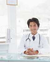 Smiling doctor sitting at his desk