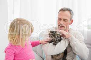 Happy daughter and father sitting with pet kitten together